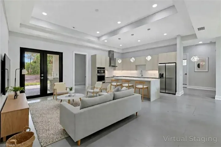 Virtual staged - Living room with finished concrete flooring, french doors, recessed lighting, and a raised ceiling