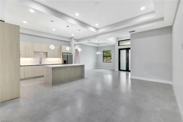 Kitchen featuring modern cabinets, concrete flooring, stainless steel refrigerator with ice dispenser, light brown cabinetry, and a kitchen island