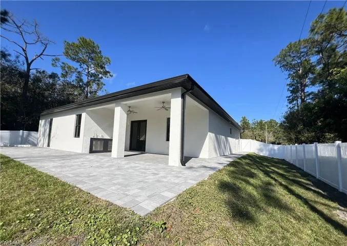 Back of property with a ceiling fan, a fenced backyard, stucco siding, and a patio