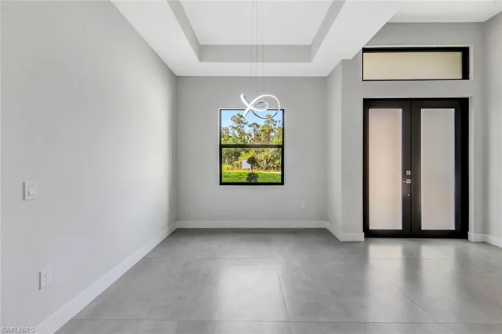 Empty room with concrete floors, french doors, and a raised ceiling