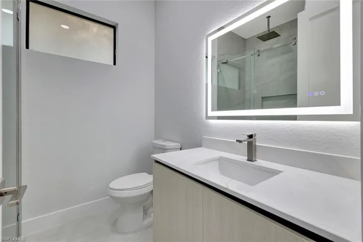 Bathroom with a textured wall, a marble finish shower, and vanity