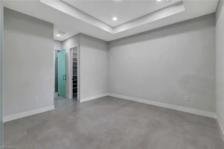 Empty room featuring concrete floors, a tray ceiling, and recessed lighting