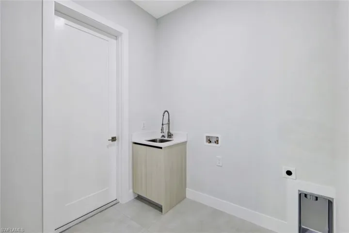 Washroom with washer hookup, hookup for an electric dryer, and light tile patterned floors