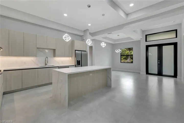 Kitchen featuring a kitchen island, hanging light fixtures, and light brown cabinetry