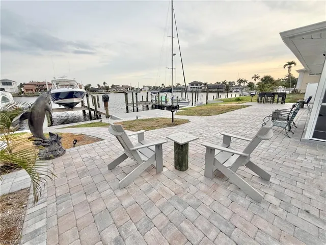 Patio terrace at dusk featuring boat lift, a dock, and a water view