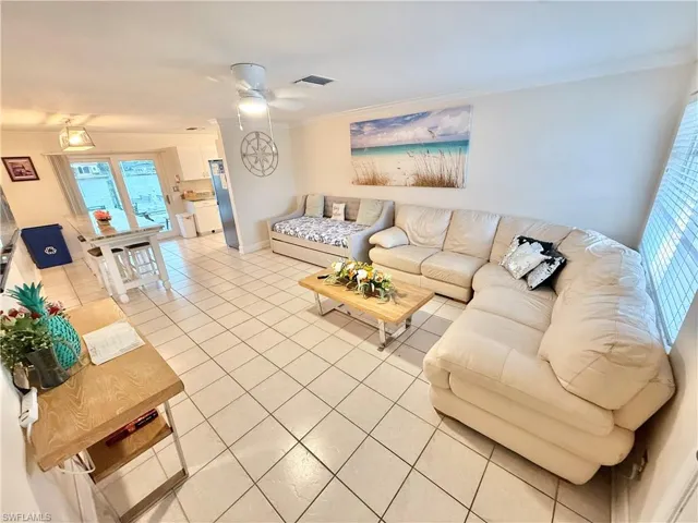 Living area featuring ornamental molding, light tile patterned floors, ceiling fan, and baseboards