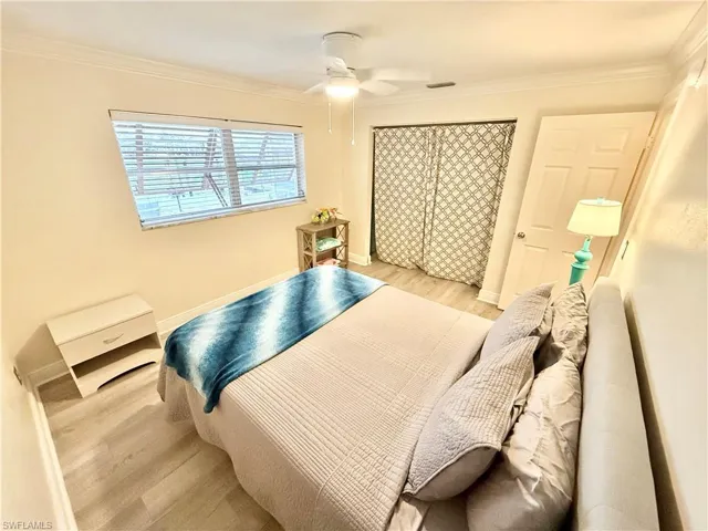 Bedroom featuring wood finished floors, crown molding, a ceiling fan, and baseboards