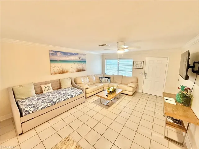 Living area featuring crown molding, light tile patterned flooring, ceiling fan, and baseboards