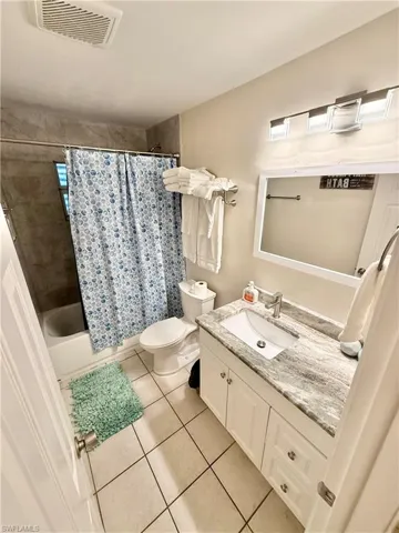 Bathroom with tile patterned floors, vanity, toilet, and shower / bath combination with curtain