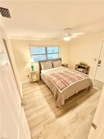 Bedroom with wood finished floors, ornamental molding, baseboards, and a ceiling fan