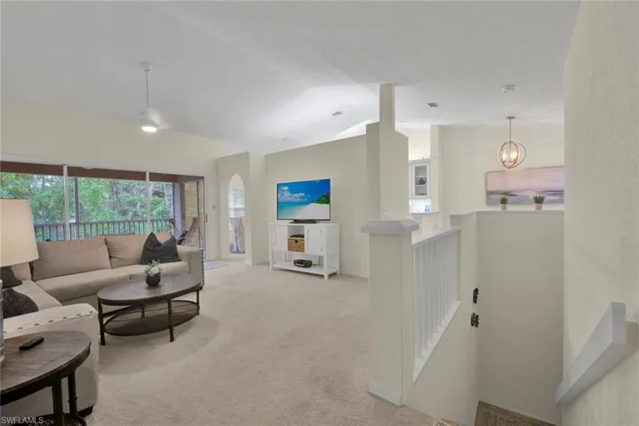 Carpeted living area featuring arched walkways and a high ceiling