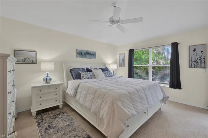 Bedroom featuring light colored carpet, a ceiling fan, and a textured wall