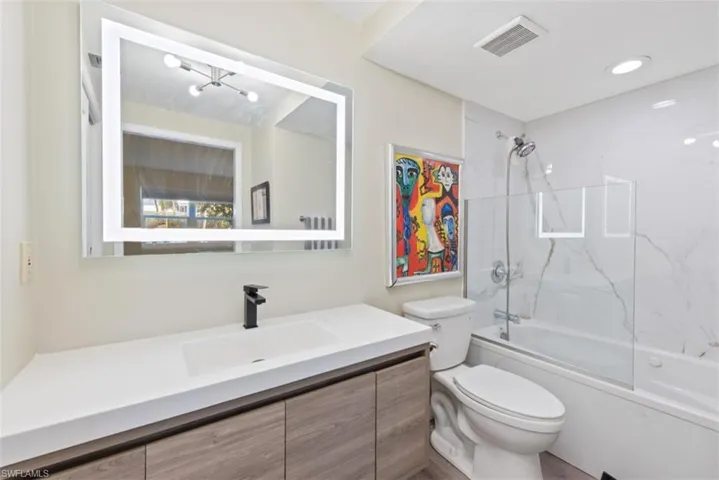Full bathroom featuring vanity, toilet, and bath / shower combo with glass door