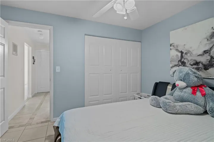Bedroom with light tile patterned floors, a closet, ceiling fan, and inlaid floor details