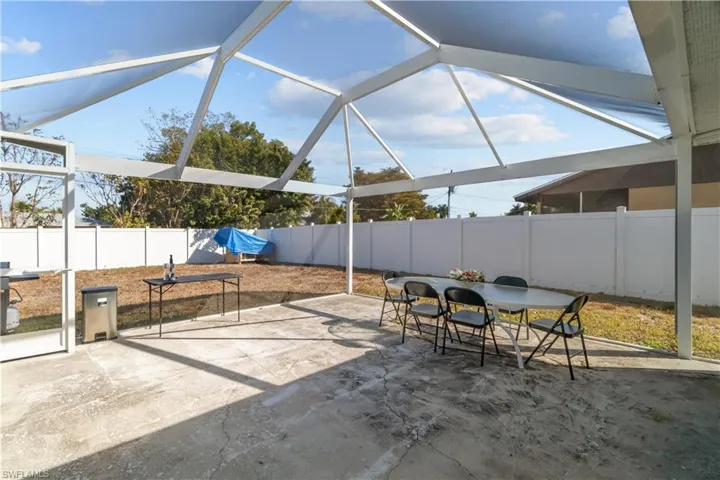 Fenced backyard featuring a sunroom, outdoor dining space, a lanai, and a patio