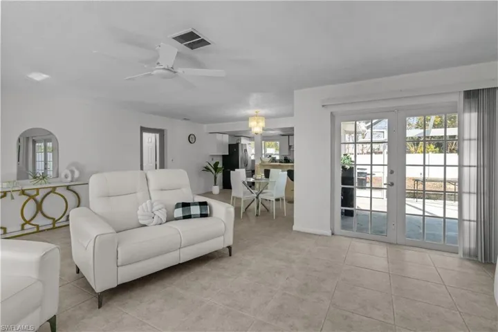 Living area with ceiling fan, french doors, and light tile patterned floors