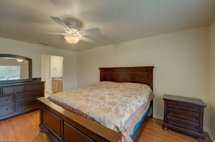 Bedroom featuring ceiling fan, light wood-type flooring, and ensuite bathroom