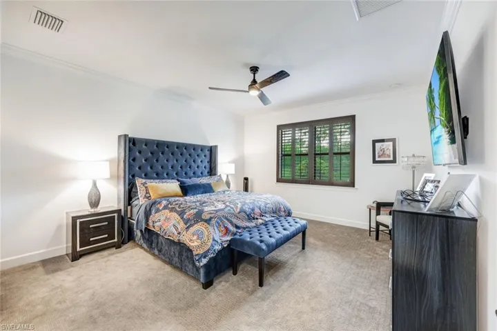 Carpeted bedroom featuring ornamental molding and a ceiling fan