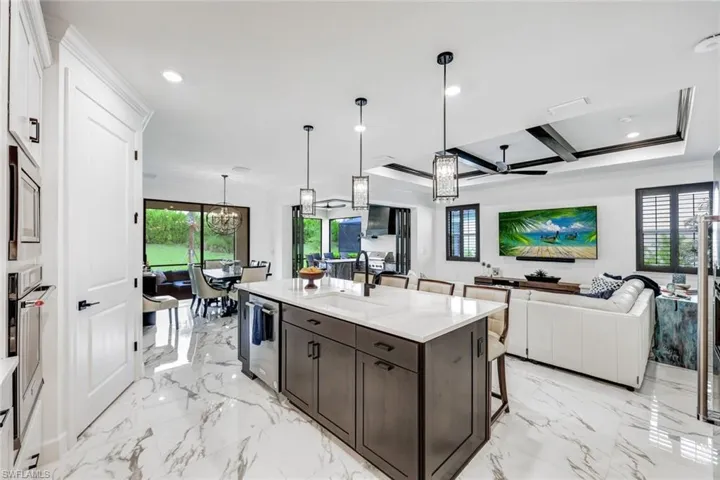 Kitchen with a breakfast bar, pendant lighting, light stone countertops, open floor plan, and a chandelier