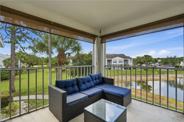 Screened balcony with concrete flooring, showcasing a tranquil pond and lush green landscaping