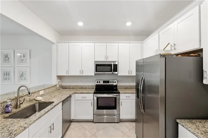 Bright, functional kitchen with white shaker-style cabinetry, stainless steel appliances, granite countertops, and recessed lighting.