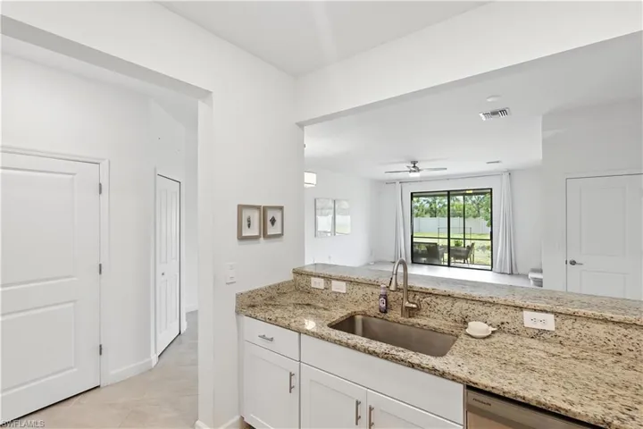 Open-concept kitchen featuring granite countertops, breakfast bar, and views into the main living area and screened lanai beyond.