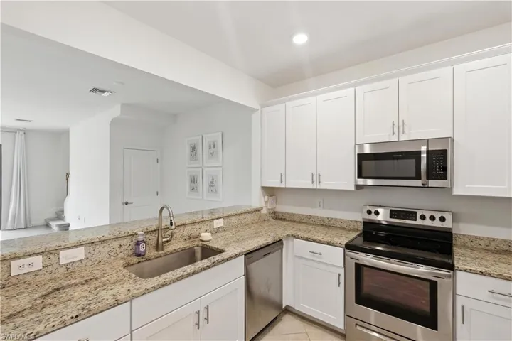 Bright, functional kitchen with white shaker-style cabinetry, stainless steel appliances, granite countertops, and recessed lighting.