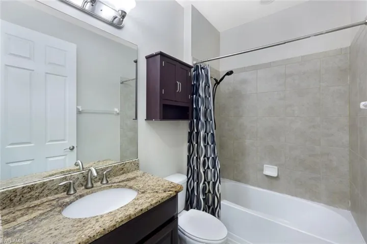 Vanity with a granite countertop, undermount sink, and brushed nickel faucet
