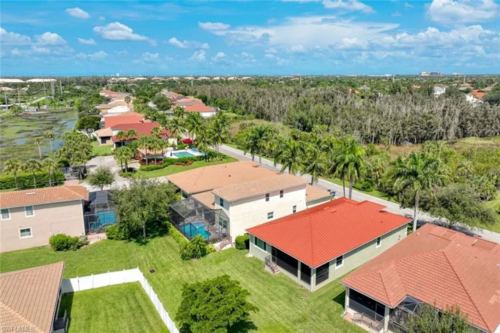Aerial overview featuring multiple residential properties with tiled roofs, screened-in pools, and manicured lawns