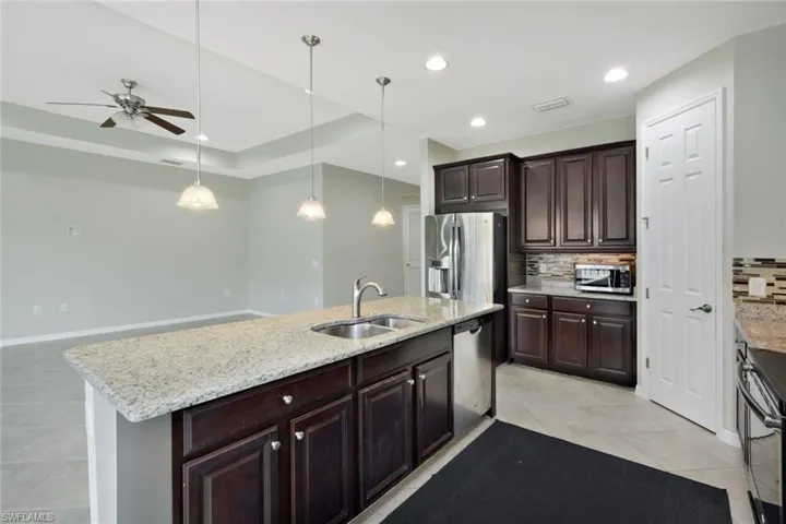 Kitchen featuring dark wood cabinetry, light-colored granite countertops, and stainless steel appliances
