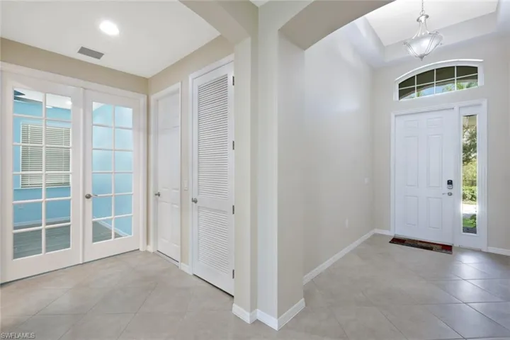Foyer featuring a decorative front door with a transom window and sidelight, a tray ceiling with a chandelier, and diagonal tile flooring
