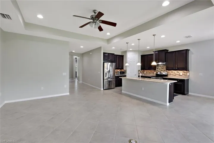 Open-concept living area featuring a kitchen with dark wood-finish cabinetry, stainless steel appliances, and a central island with pendant lighting
