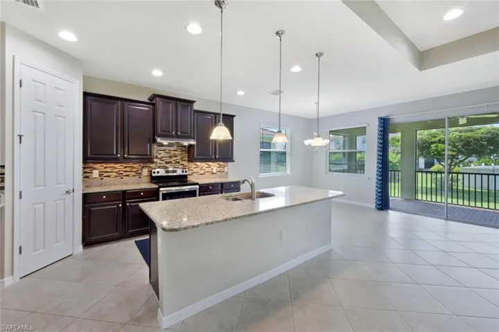 Kitchen featuring dark wood cabinetry, a tiled backsplash, and stainless steel appliances