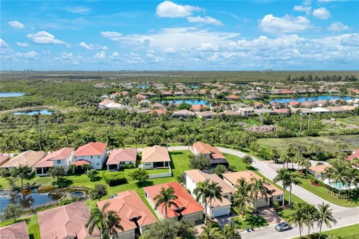 Aerial perspective featuring multiple residential structures, lush landscaping, and prominent water features
