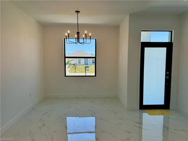 Tiled spare room with an inviting chandelier