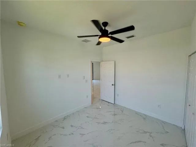 Empty room with ceiling fan and light tile floors
