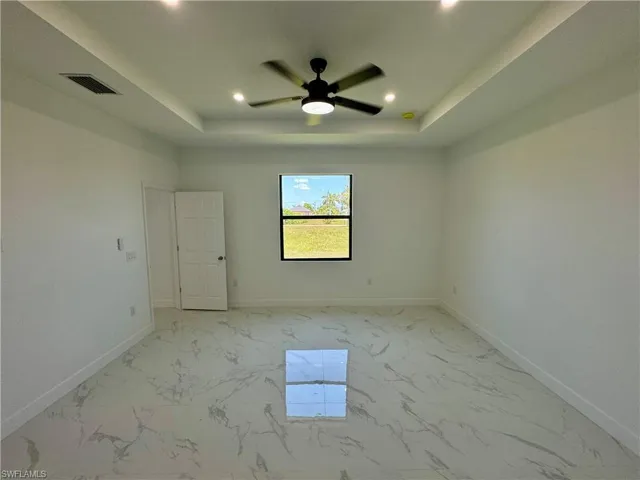 Unfurnished room with ceiling fan, a raised ceiling, and light tile floors