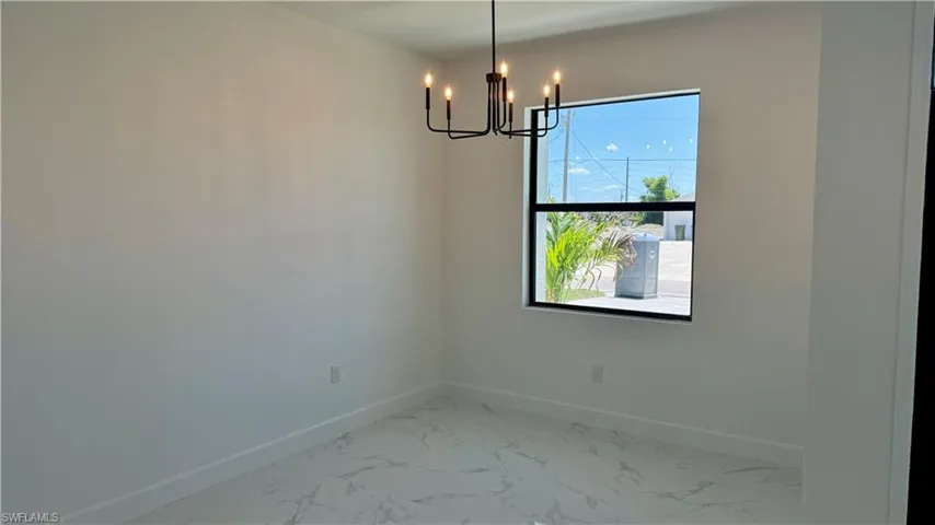 Empty room featuring a notable chandelier and tile flooring