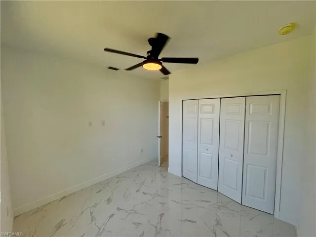 Unfurnished bedroom featuring ceiling fan, a closet, and light tile floors