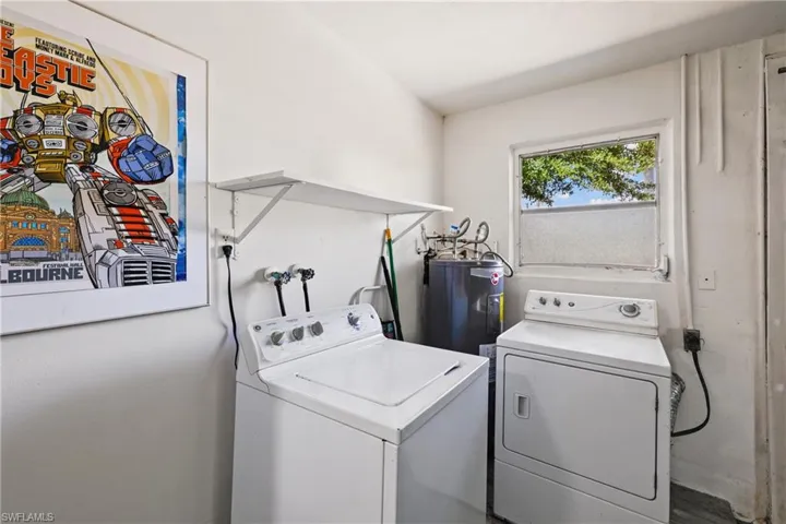 Clothes washing area featuring hookup for a washing machine, washer and clothes dryer, electric dryer hookup, and water heater