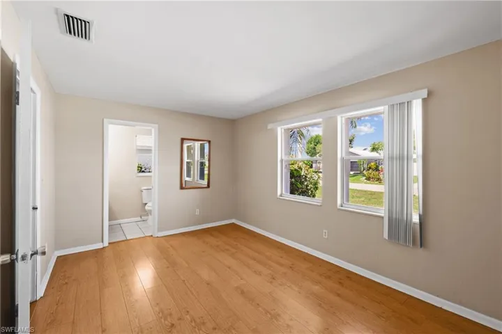 Unfurnished bedroom with ensuite bath and light wood-type flooring