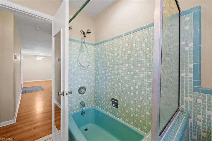 Bathroom with tiled shower / bath, ceiling fan, hardwood / wood-style flooring, and tile walls