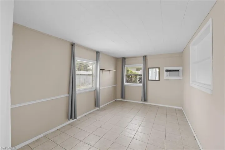 Empty room with light tile floors and an AC wall unit