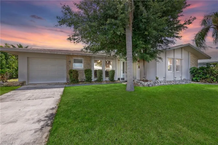 Single story home featuring a garage and a lawn