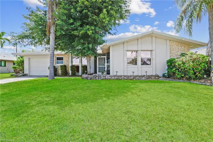 Ranch-style house with a garage and a front lawn