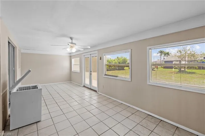 Tiled empty room featuring ceiling fan and french doors