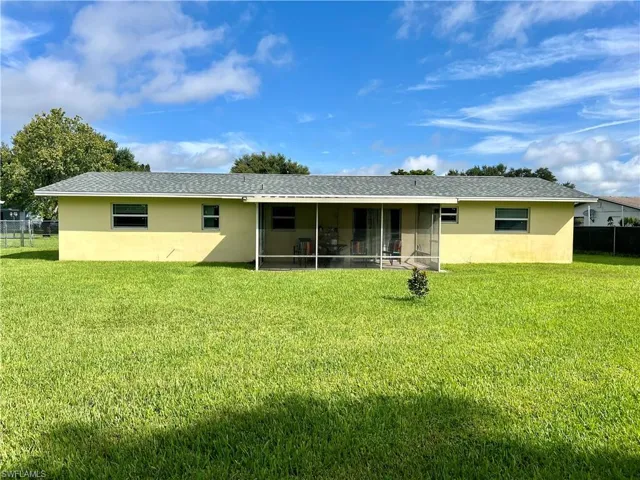 Rear view of property with a yard and a sunroom