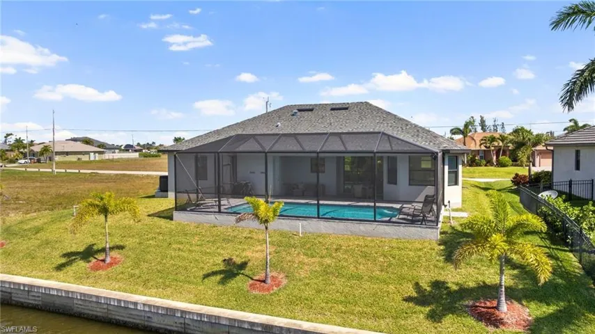Back of property with glass enclosure, a fenced in pool, a patio, and a lawn