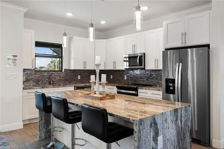 Kitchen featuring ornamental molding, a center island, appliances with stainless steel finishes, and backsplash