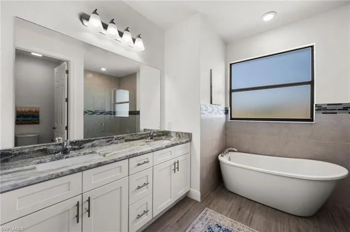 Full bathroom featuring a shower stall, double vanity, a sink, and toilet